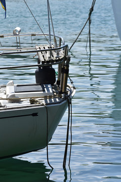 Boat stern with railing and ropes disappearing under calm water surface.