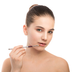 Portrait of beautiful young brunette woman with clean face. Beauty spa model girl with perfect fresh clean skin applying cosmetic brush. Youth and skin care concept. Isolated on a white background.