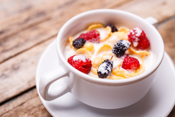 Close up image of corn flakes with berry and milk