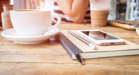 Mobile phone and diary notebook with coffee cup on wood backgrou