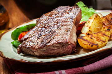 Portions of grilled beef steak with grilled potatoes and paprika