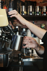Fototapeta na wymiar Woman barista making espresso coffee and frothing milk