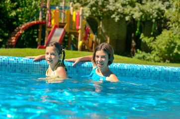 Kids in swimming pool have fun and splash in water, children on family vacation
