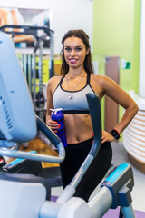Fit woman doing exercise on a elliptical trainer.