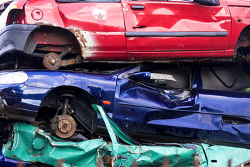 three colorful discarded scrap cars stacked on a junkyard, color stripes concept