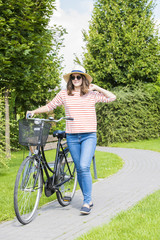 Obraz premium Get out and ride. Full length portrait of a young woman pushing a bicycle in the park.