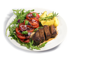 roasted beef filet mignon with potatoes and tomato arugula salad isolated on white