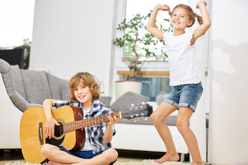 Mädchen tanzt glücklich und Junge spielt Gitarre