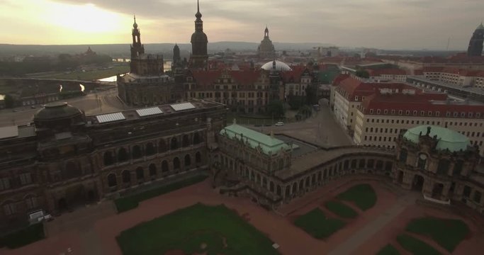 Aerial camera flies backwards away from the Dresden skyline and over the Zwinger Palace. Shot on a cloudy morning at dawn