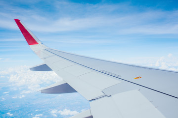 Obraz premium Wing of airplane flying above clouds blue sky background