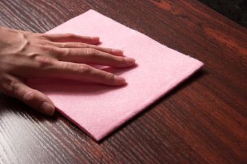 Wiping wooden shelf from dust.