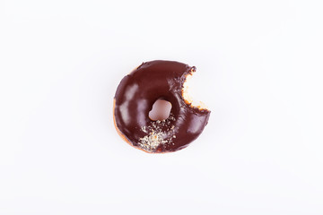 Chocolate bitten donut with glaze and sprinkles on a dark background. Top view with copyspace