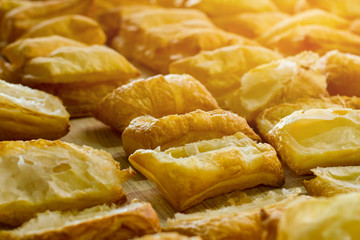Puff pastry on wooden board. Lots of baked products. Income of cafe is growing. Dough without filling.