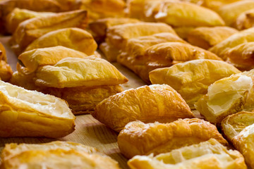 Rows of yellow puffs. Pastry on light wooden board. Income of bakery is growing. Sweet airy dough.