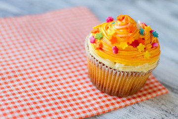 Cupcake on red napkin. Bright-colored icing. Choose best dessert at cafe. Tiny sugar flowers.