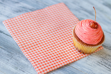 Pink cupcake and red napkin. Berry on colorful frosting. Confectionery in local cafe. Simple baked dessert.