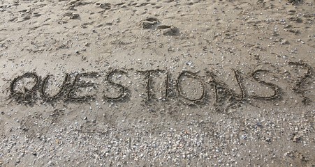 questions written on the beach sand