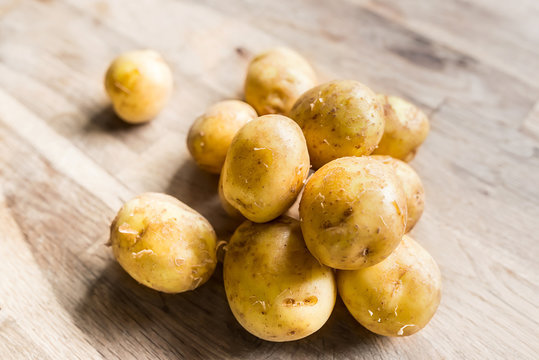 Beautiful Pile Of Small Rounded Whole Organic Potatoes With The Peel Isolated On An Old Oak Cutting Board With Focal Blur