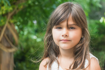 Portrait of attractive little girl with long hair. Girl is looking at the camera.