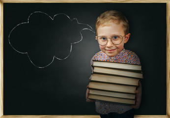 Boy with books near school chalkboard
