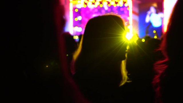 Unrecognizable performing singer and audience silhouettes at night live show. 4K background bokeh shot