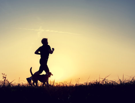 Runner and dog silhouttes in sunset light