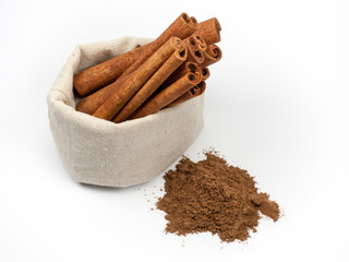 Bunch of cinnamon in canvas bag and cinnamon powder isolated on white background