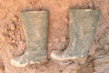 Verschmutzte Gummistiefel im Sand