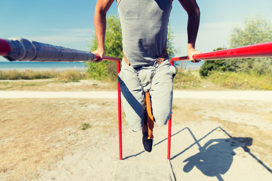 young man exercising on parallel bars outdoors