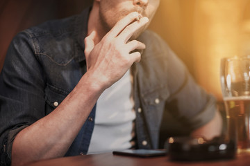 man drinking beer and smoking cigarette at bar