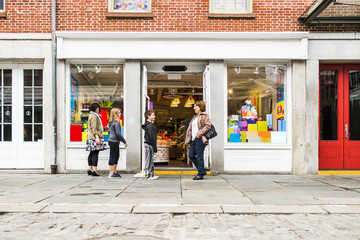 Side view of people standing on sidewalk outside candy shop in city