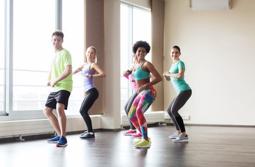 group of smiling people dancing in gym or studio