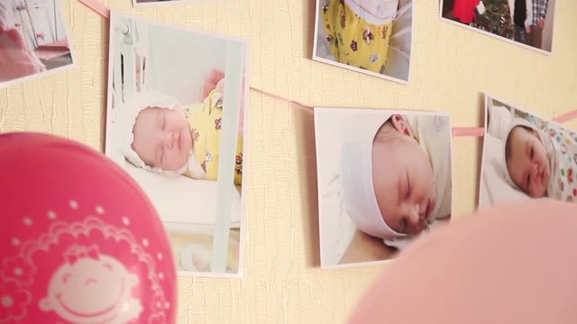 Newborn baby photos hanging on the wall with balls.