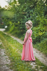 Fototapeta na wymiar A beautiful portrait of a girl in evening dress among the garden