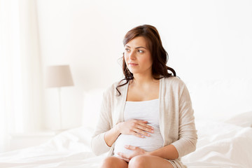 Obraz na płótnie Canvas happy pregnant woman sitting on bed at home