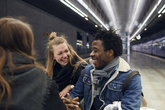 Friends standing on railroad platform, laughing