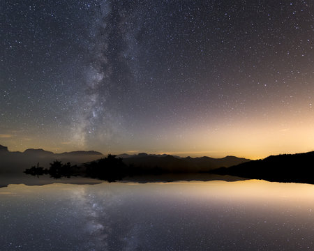 Tranquil landscape with star reflection and milky way