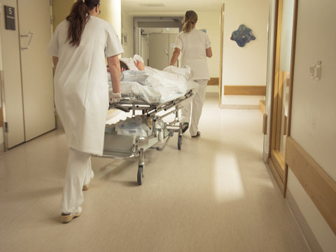 Nurse Pushing Patient On Gurney In Hospital