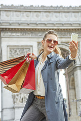 woman shopper near Arc de Triomphe taking selfie with cellphone