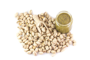 un vasetto di pesto di pistacchi e un cucchiaio di legno con dei pistacchi crudi