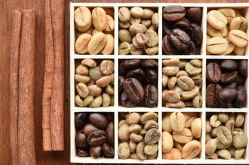 Coffee beans in wooden box and cinnamon on wooden background