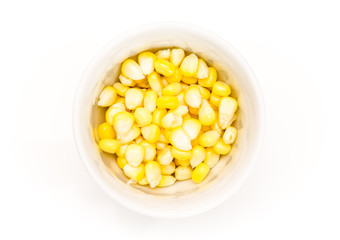 Corn kernels in a white bowl, on white background.