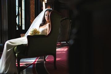 Young bridal sitting on chair in a dark room