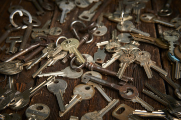 Pile of keys on a grunge wooden background.