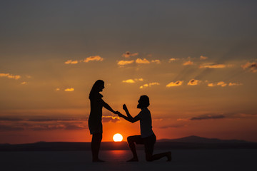 Fototapeta na wymiar Young couple on sunset, he asking for married