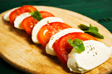 Sandwich from sliced tomatoes, mozzarella, basil and baguette 
