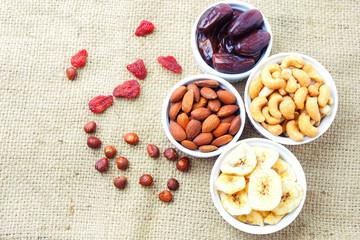 Top view of a bowl of healthy mixed dried fruit and nuts on a sackcloth. 