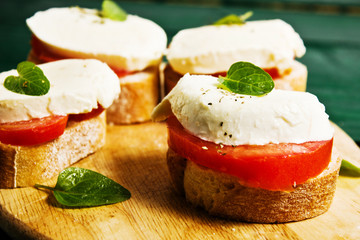 Sandwich from sliced tomatoes, mozzarella, basil and baguette 