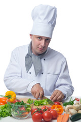 Cook cuts the greens at a table with vegetables