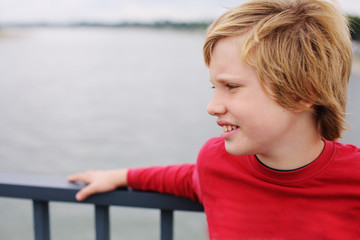 Portrait of cute 8 years old boy standing on the bridge